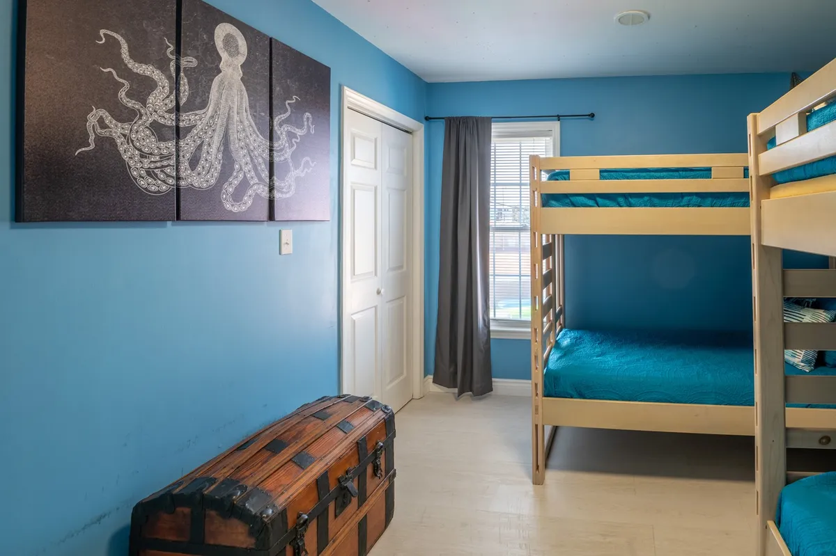 A playful and imaginative bedroom with octopus artwork, bunk beds, and a wooden chest. The decor is whimsical and nautical, ideal for children or those young at heart.