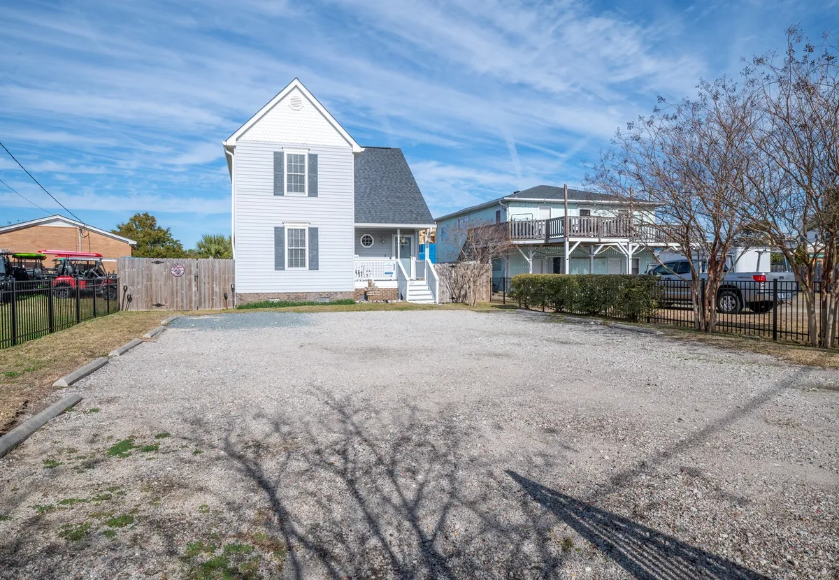 A daylight exterior view of the main house and an adjacent building, with an open parking area and a spacious yard visible. The setup invites outdoor activities, gatherings, and play, with plenty of space for pets and their owners to enjoy the fresh air.