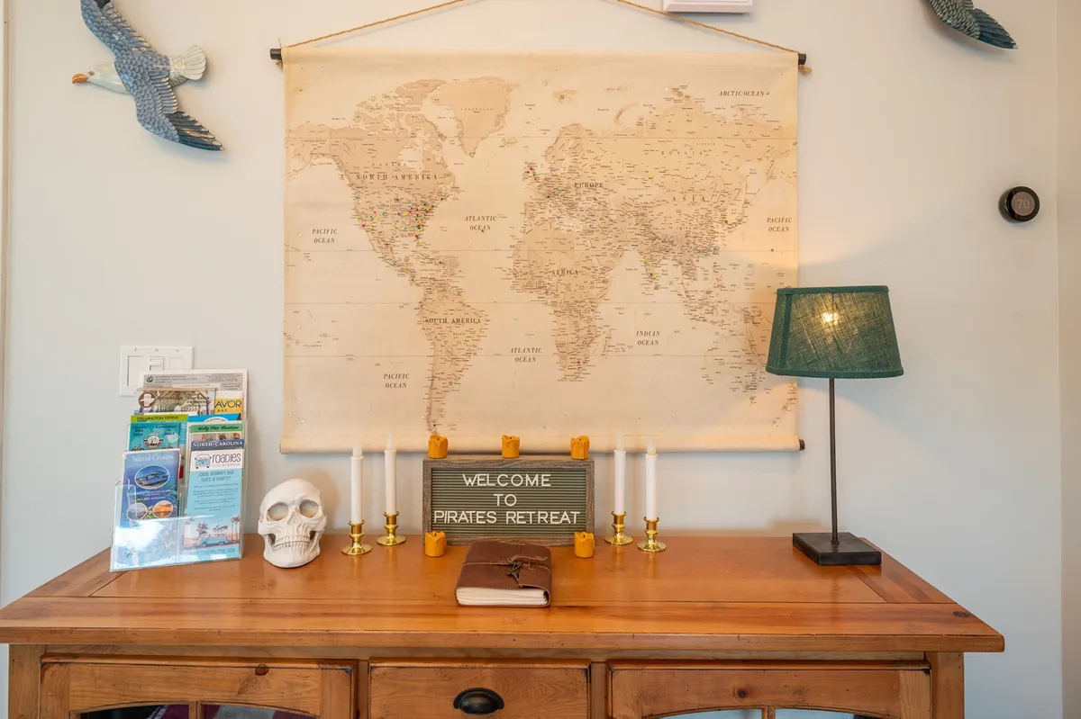 A playful tabletop scene featuring a world map, a whimsical welcome sign, candles, a decorative skull, and a table lamp. Nautical and adventure-themed décor invite exploration and set a lively, imaginative tone for the space.
