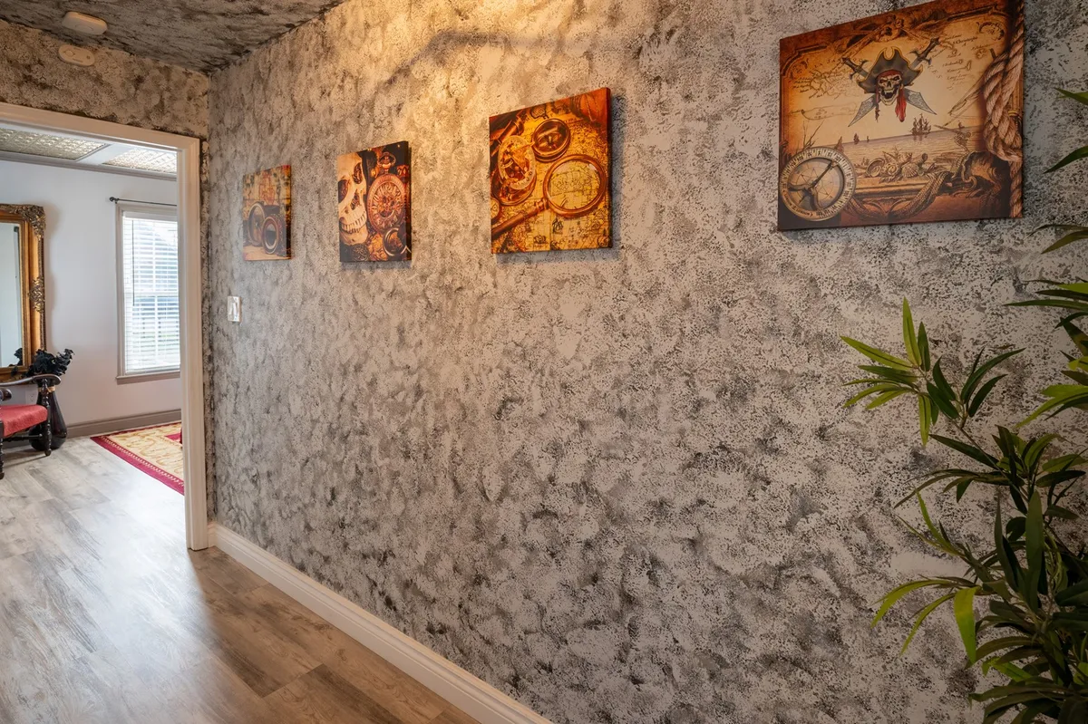 A hallway filled with whimsical, decorative wall art and lush indoor plants, exuding a sense of adventure and curiosity. The textured walls and playful decor make for a unique backdrop, hinting at the retreat’s thematic personality.
